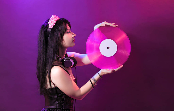 Giovane donna DJ con vinile rosa gode di musica. Glamour ragazza con headphne su sfondo viola riproduce musica disko
. - Foto, immagini