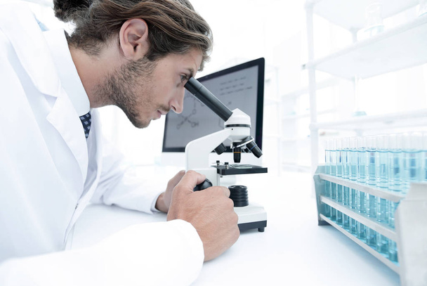 Young laboratory scientist looking at microscope in laboratory - Foto, Imagen
