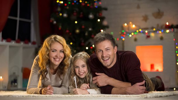 Happy family smiling at camera, composing letter to Santa, belief in fairy-tale - Fotó, kép