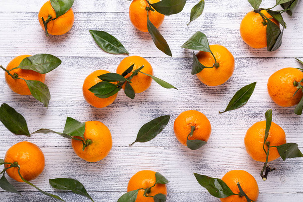 Fresh orange mandarins, tangerine with green leaves on white wooden background. Top view - Fotografie, Obrázek