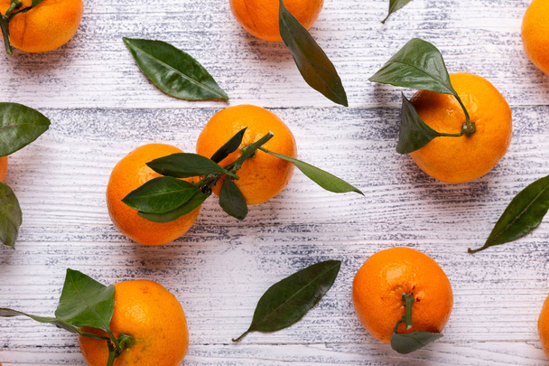 Fresh orange mandarins, tangerine with green leaves on white wooden background. Top view - Foto, imagen