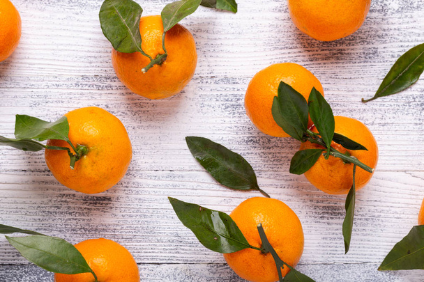 Fresh orange mandarins, tangerine with green leaves on white wooden background. Top view - Foto, Imagem