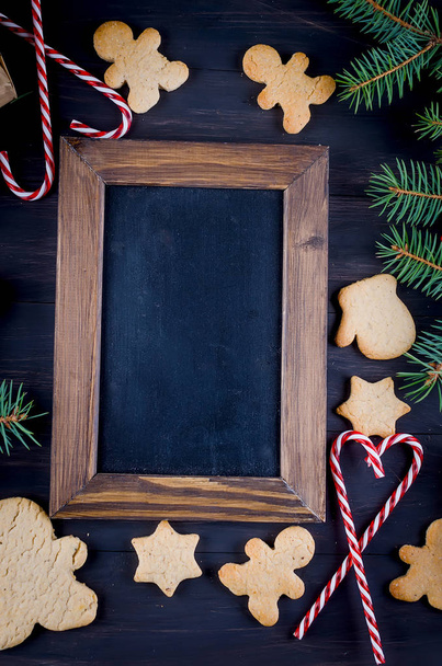 Christmas composition with empty plases with many gingerbread, fir branches and gift box on dark wooden table. Holiday concept background, top view, copy spase - Φωτογραφία, εικόνα