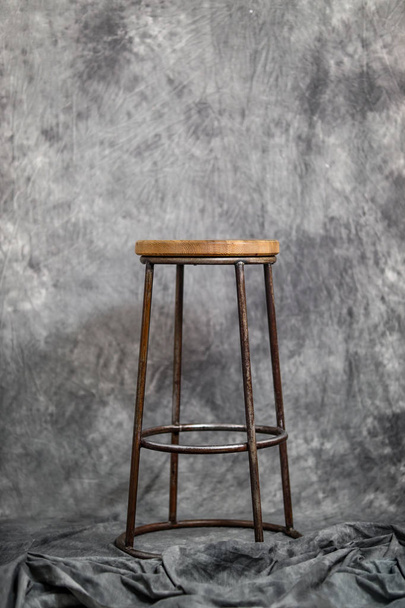 металлический стул с деревянным сиденьем на сером фоне ткани
 - Фото, изображение