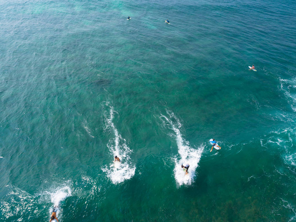 Aerial view from drone of surfers paddling for catching waves during surfing  in the indian ocean - Фото, зображення
