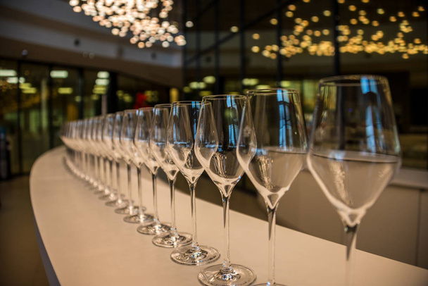 Een aantal glazen staan op een lange tafel, bereid voor champagne. - Foto, afbeelding