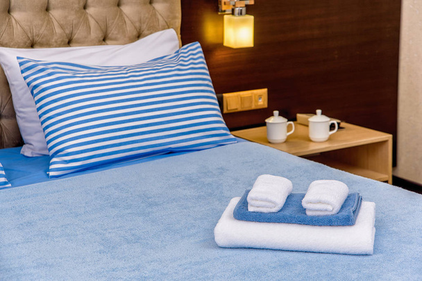 Bettwäsche und Baumwollhandtücher. Set himmelblaue Bettwäsche. Kissen mit blauem Streifenmuster. Handtücher in verschiedenen Größen für den Hotelkomplex. Naturtextilien aus Baumwolle im Innenraum. - Foto, Bild