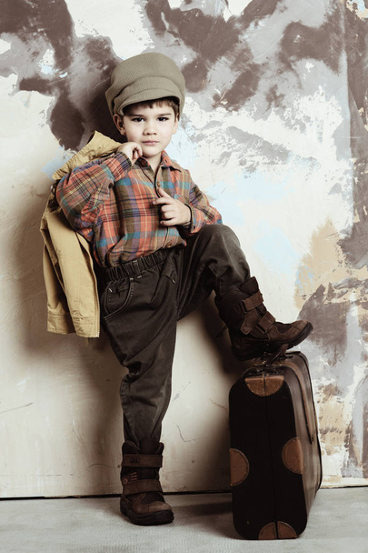 Boy wearing vintage puts his leg on suitcase, retro stylized shot, 50s-60s - Foto, afbeelding