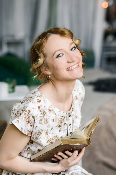 Portrait of a beautiful woman in a vintage dress with an old book in her hands - Foto, afbeelding