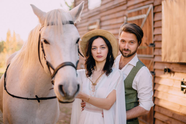 stylish newlyweds stand near horse and look into camera - Foto, Imagen