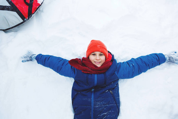 ładny, młody chłopak w kapelusz niebieski kurtka posiada i bawi się śniegu, ma zabawy, uśmiechy, sprawia, że snowman w winter park. Aktywny tryb życia, zimowa, zewnątrz zima gry, śnieżkami.  - Zdjęcie, obraz