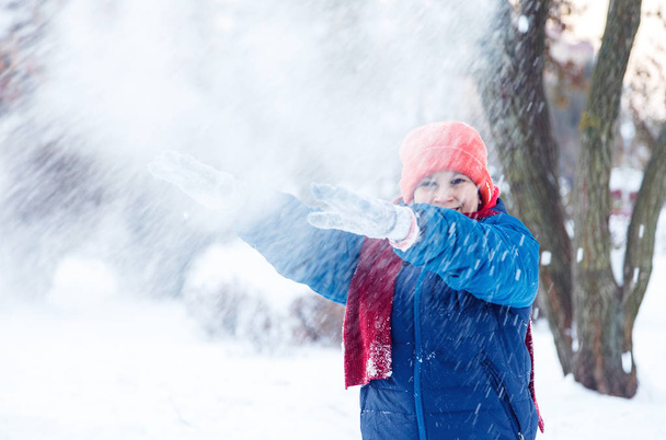 roztomilý mladý chlapec v hat modrá bunda drží a hraje se sněhem, má zábavu, úsměvy, dělá sněhulák v zimě parku. Aktivní životní styl, zimní aktivity, zimní venkovní hry, sněhové koule.  - Fotografie, Obrázek