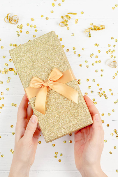 New Year or Christmas pattern flat lay top view Xmas holiday celebration decorative golden gift box sparkles white wooden background copy space Template frame for greeting card your text design - Photo, Image