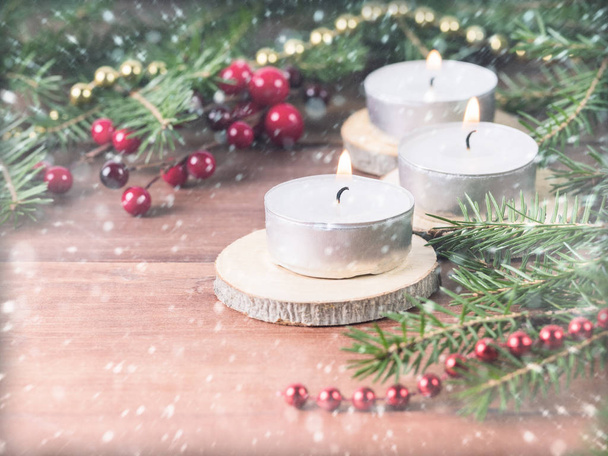 White candles on a wooden stand against a background of a blurred background of spruce fir - Valokuva, kuva