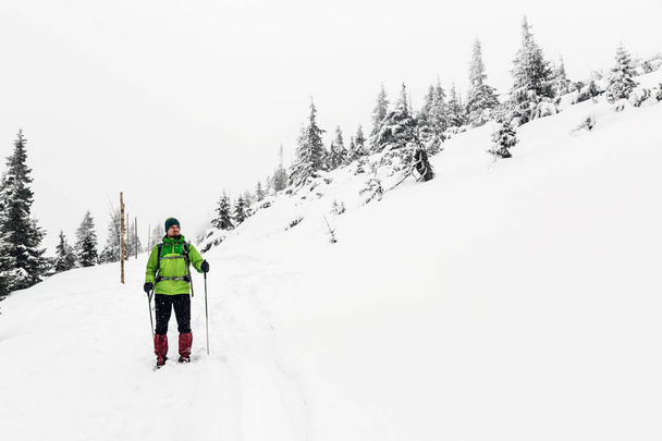 白い森で冬のトレッキング。男は白い冬の森でトレッキング ハイキングします。レクリエーション フィットネスや屋外で雪に覆われた自然が美しい健康的なライフ スタイルを旅行します。モチベーションとインスピレーションの白い冬の風景. - 写真・画像