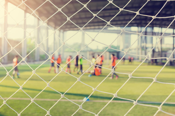 Beyaz kafes amacı ile koç ile yeşil yapay çim üzerinde oturan bulanık genç çocuk futbol oyuncuları. - Fotoğraf, Görsel