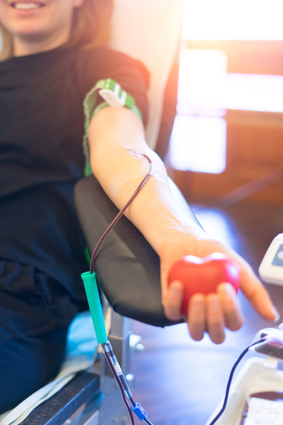 young woman as blood donor at donation with a bouncy ball holding in hand - Photo, Image