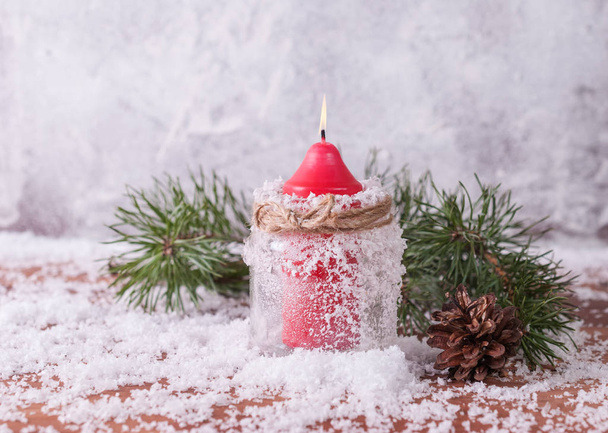 Candle, cones and spruce branches on a snow-covered wooden background - Foto, Imagen