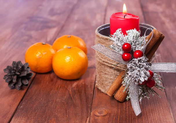 New Year's composition with a red candle in a candlestick, mandarins, a New Year's decor. - Fotografie, Obrázek