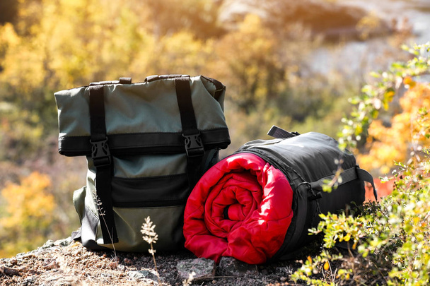 Backpack and sleeping bag on ground outdoors. Camping equipment - Fotó, kép