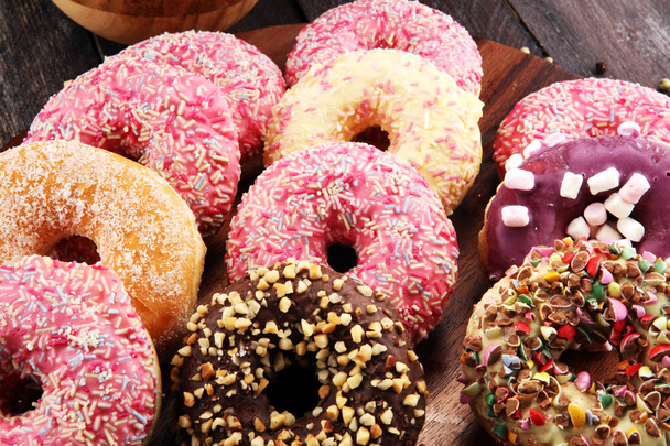 разнообразные пончики с шоколадом глазированные, розовые глазурованные и посыпать пончики. - Фото, изображение