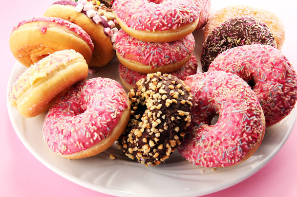 verschiedene Donuts mit Schokolade gefrostet, rosa glasiert und bestreut Donuts. - Foto, Bild