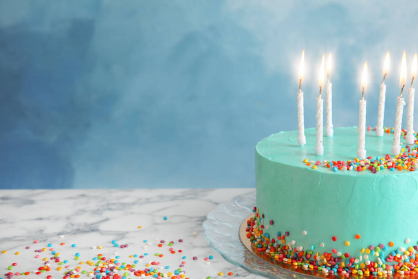 Fresh delicious birthday cake with candles on table against color background. Space for text - 写真・画像