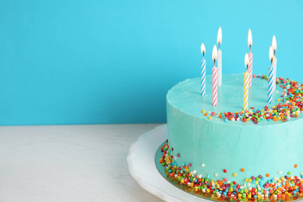 Fresh delicious birthday cake with candles on table against color background. Space for text - Photo, Image