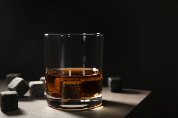 Golden whiskey in glass with cooling stones on table. Space for text - Foto, afbeelding