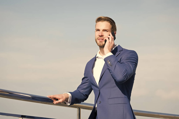 Man with smartphone on terrace on blue sky, business communication - Foto, imagen