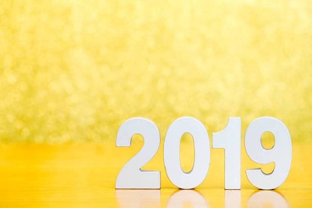 Number 2019 for happy new year on wooden table and golden bokeh background - Fotó, kép