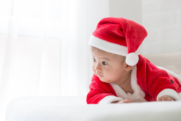 Asiático bebé niño en Santa Claus vestido en la cama blanca para el día de Navidad y feliz año nuevo festival
 - Foto, Imagen