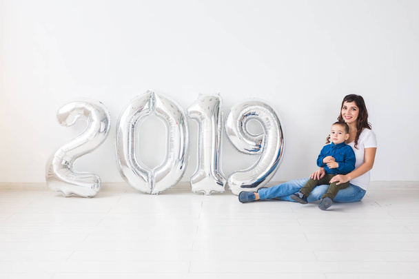 Újévi 2019 fogalom - boldog anya és fia, ezüst színű számok beltéri jön. - Fotó, kép