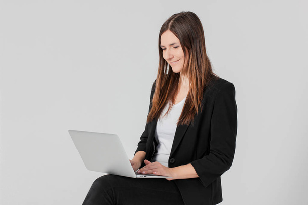 Portrait of young smiling brunette woman lady in business suit with laptop isolated on grey background - Fotoğraf, Görsel