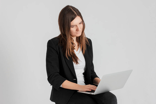 Portrait of worried tired brunette woman lady in business suit with laptop isolated on grey background - Fotoğraf, Görsel