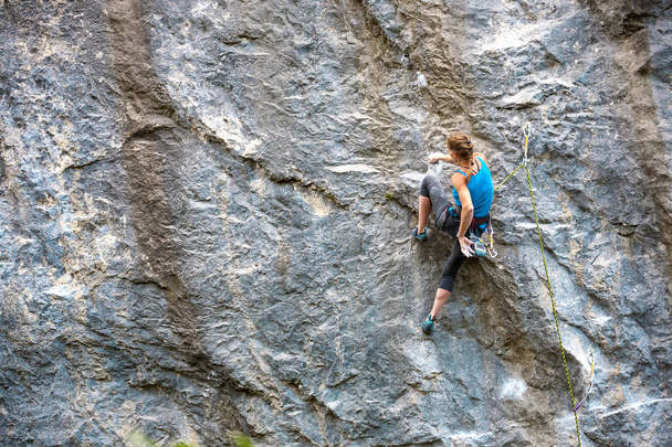 Ο ορειβάτης είναι η εκπαίδευση να ανεβείτε στο βράχο. Ισχυρή κορίτσι υπερνικά μια διαδρομή δύσκολη αναρρίχηση. Ενεργό τρόπο ζωής. Ακραία χόμπι. Μια γυναίκα πηγαίνει σε για σπορ στη φύση. - Φωτογραφία, εικόνα