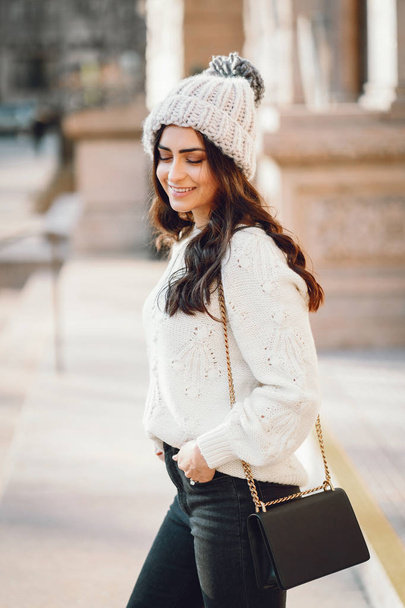 Cute brunette in a white sweater in a city - Fotó, kép
