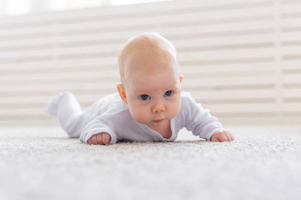 childhood, people concept - baby girl learning to crawl on the floor. - 写真・画像