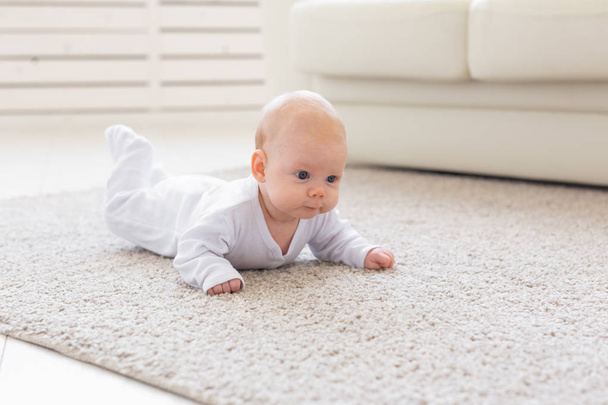 Childhood, babyhood and people concept - little baby boy or girl crawling on floor at home - Photo, Image