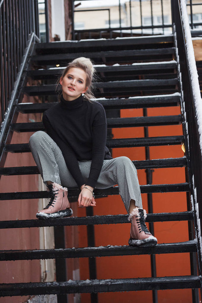 Stylish young woman in boots sitting on stairs. Winter style - Valokuva, kuva