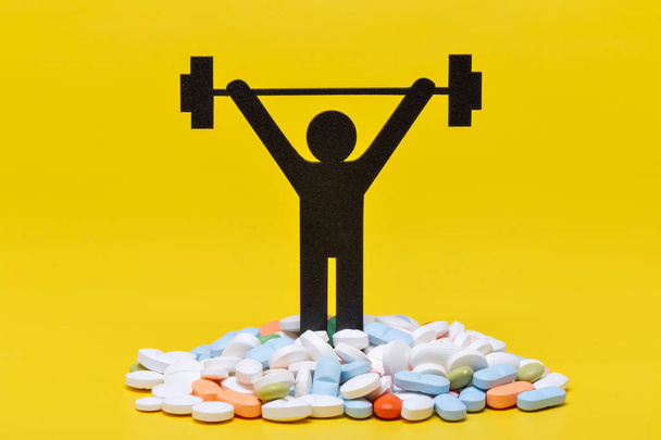 pictograma de levantamiento de pesas con pastillas y fondo amarillo
 - Foto, imagen