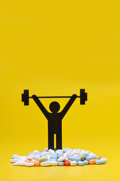 pictograma de levantamiento de pesas con pastillas y fondo amarillo
 - Foto, imagen