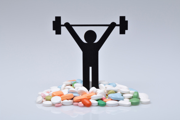 Gewichtheben-Piktogramm mit Pillen und grauem Hintergrund - Foto, Bild