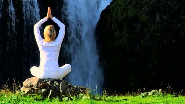 vrouw in wit uitvoeren van yoga door waterfall - Video