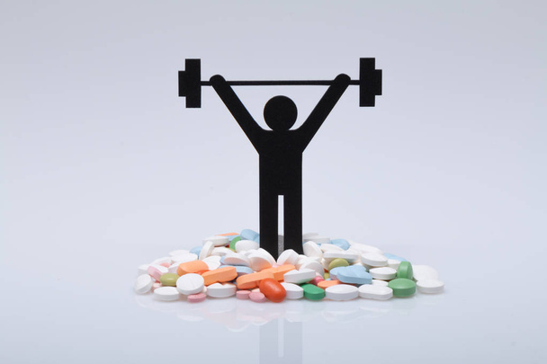 Gewichtheben-Piktogramm mit Pillen und grauem Hintergrund - Foto, Bild