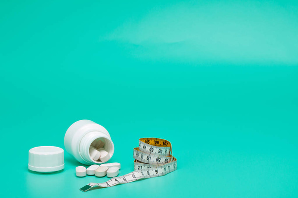 Meetlint en pillen op een helder groene achtergrond - Foto, afbeelding