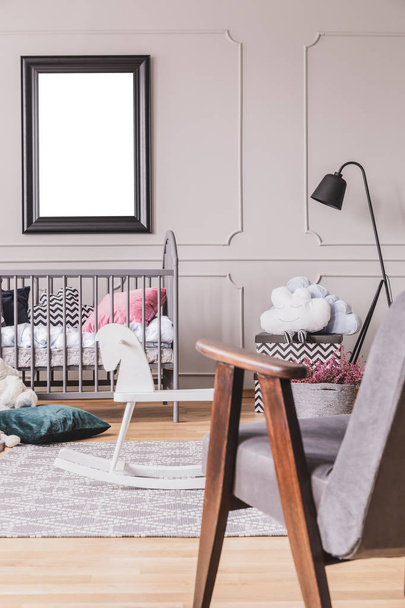 Vertical view of vintage grey armchair in trendy mid century baby room interior with mockup in black frame on the empty grey wall - Foto, Imagem
