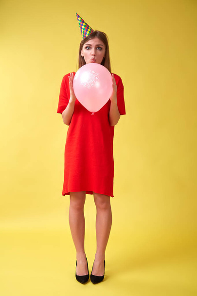 Girl in red dress and birthday hat holding a christmas balloon in her hands. - Foto, Imagem