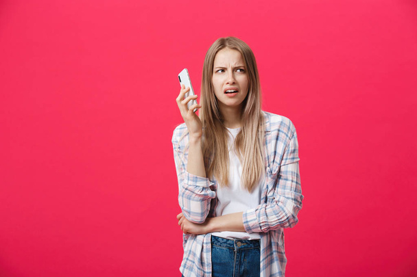 Bored girl calling on the phone and looking crazy on a pink background - Фото, изображение