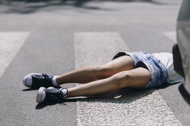 Kid hit by a car lying on a crosswalk after traffic accident - Фото, зображення